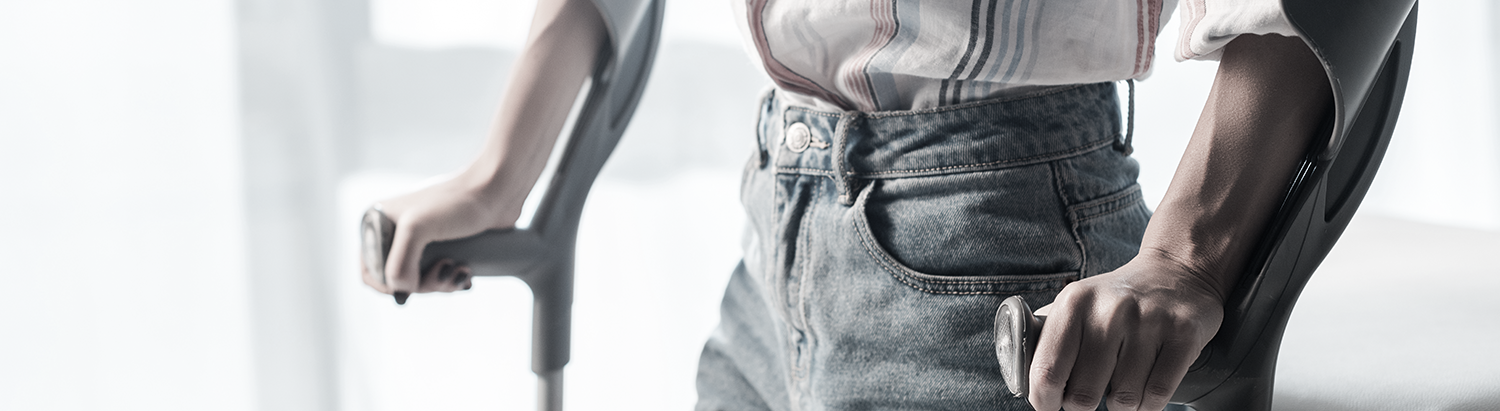 Cropped view of woman holding crutches in clinic.